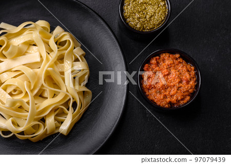 Delicious fresh pasta with pesto sauce and seafood on a black plate Delicious fresh pasta with pesto sauce and seafood on a black plate 97079439
