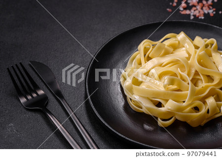 Delicious fresh pasta with pesto sauce and seafood on a black plate Delicious fresh pasta with pesto sauce and seafood on a black plate 97079441