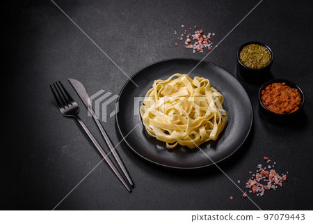 Delicious fresh pasta with pesto sauce and seafood on a black plate 97079443