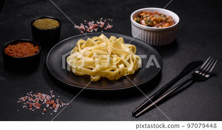 Delicious fresh pasta with pesto sauce and seafood on a black plate Delicious fresh pasta with pesto sauce and seafood on a black plate 97079448