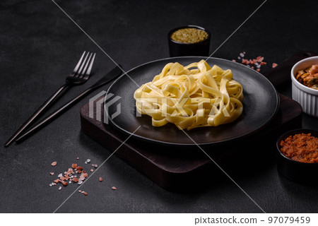 Delicious fresh pasta with pesto sauce and seafood on a black plate Delicious fresh pasta with pesto sauce and seafood on a black plate 97079459