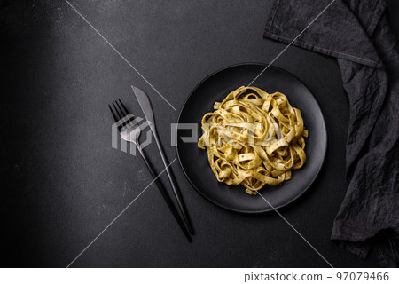 Delicious fresh pasta with pesto sauce and seafood on a black plate 97079466