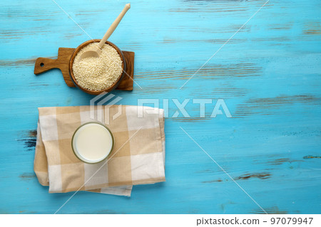 Sesame milk in a glass, raw seeds, wooden background. Dairy free alternative. Flat lay 97079947