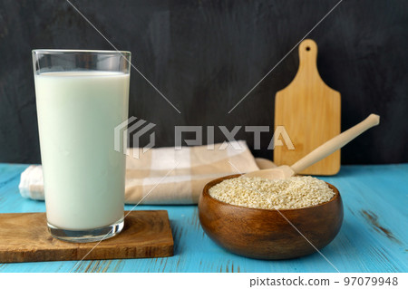 Sesame seed milk in a glass. White sesame seeds on a table. Dairy Alternative. 97079948