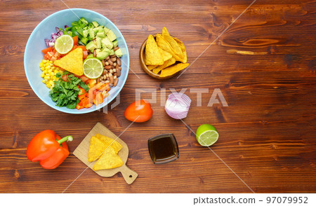 Mexican vegetable salad, cowboy caviar in bowl with ingredients and nachos. Top view. Copy space Mexican vegetable salad, cowboy caviar in bowl with ingredients and nachos. Top view. Copy space 97079952