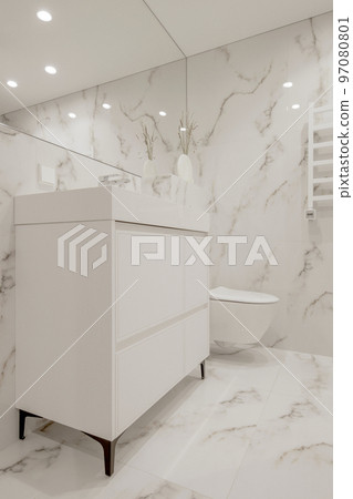 Modern minimalist white bathroom interior design with marble style tiles and white taps, vase and wall heater Modern minimalist white bathroom interior design with marble style tiles and white taps, vase and wall heater 97080801