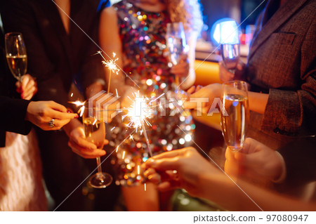 Sparkling sparklers in the hands. Playing firework to celebrate winter holidays with friends at party. 97080947