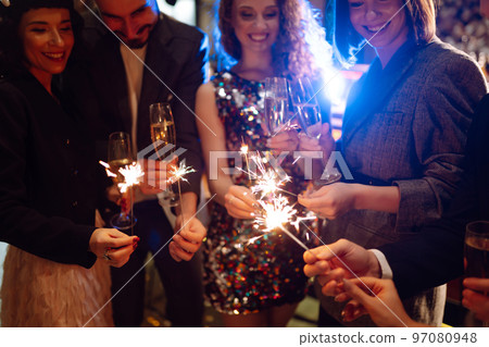 Sparkling sparklers in the hands. Playing firework to celebrate winter holidays with friends at party. 97080948