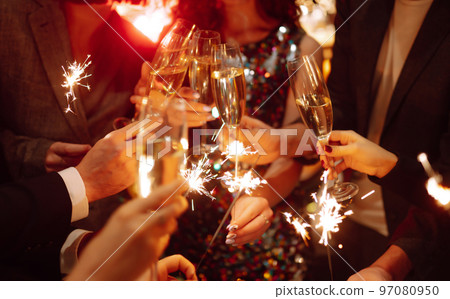 Sparkling sparklers in the hands. Playing firework to celebrate winter holidays with friends at party. Sparkling sparklers in the hands. Playing firework to celebrate winter holidays with friends at party. 97080950