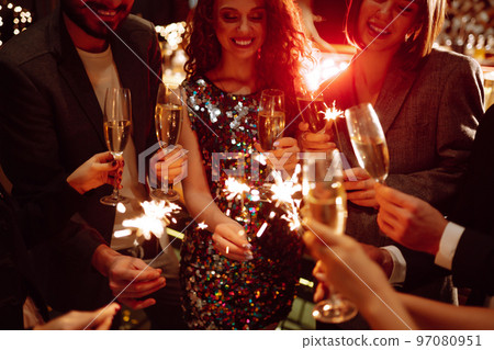 Sparkling sparklers in the hands. Playing firework to celebrate winter holidays with friends at party. Sparkling sparklers in the hands. Playing firework to celebrate winter holidays with friends at party. 97080951