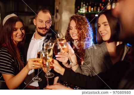 Cheering and drinking cocktails. Group of friends partying in a nightclub and toasting drinks cocktails. 97080980