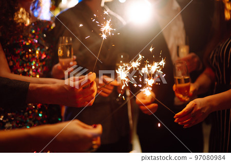 Glowing sparkles in hands. Group of happy people enjoying party with fireworks. Winter holiday. Glowing sparkles in hands. Group of happy people enjoying party with fireworks. Winter holiday. 97080984