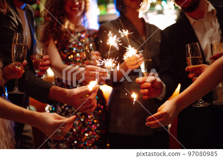 Glowing sparkles in hands. Group of happy people enjoying party with fireworks. Winter holiday. Glowing sparkles in hands. Group of happy people enjoying party with fireworks. Winter holiday. 97080985