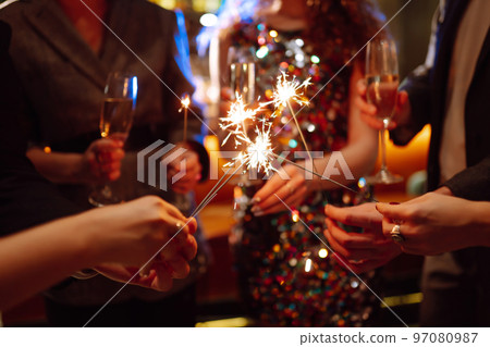 Glowing sparkles in hands. Group of happy people enjoying party with fireworks. Winter holiday. Glowing sparkles in hands. Group of happy people enjoying party with fireworks. Winter holiday. 97080987