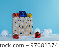 A paper bag filled with gifts stands in the snow. Christmas decorations. 97081374