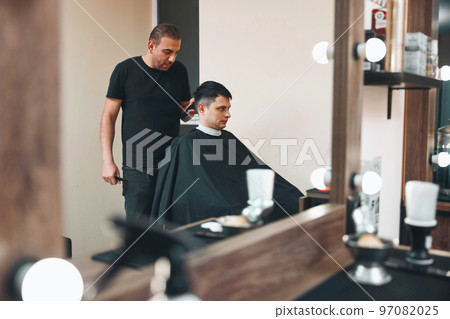 Barber shaving caucasian man in barber shop 97082025
