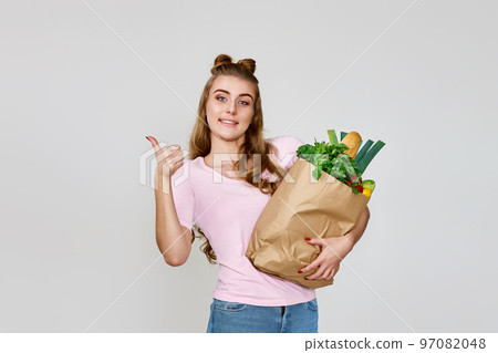 girl holds paper bag with vegetables, measuring tape and showing thumbs up 97082048