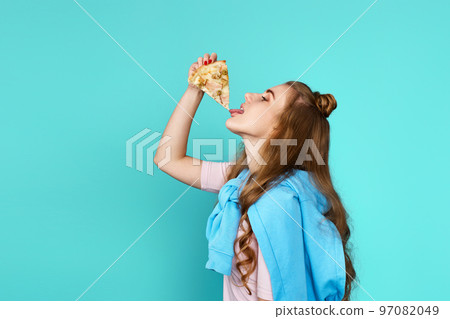 woman eating pizza slice and looking delighted 97082049
