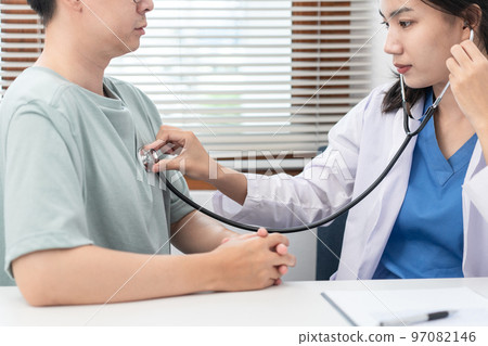Female doctor physician is examines heart and lungs of male patient with a stethoscope to check 97082146
