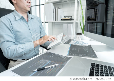 Male programmer is programming to develop program app and website of corporate while working to checking program code and debugging on multiple screen at modern software office 97082286