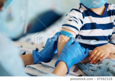 Vaccination of little child at home. Children's hand with funny adhesive plaster. Vaccine for covid-19. 97082528