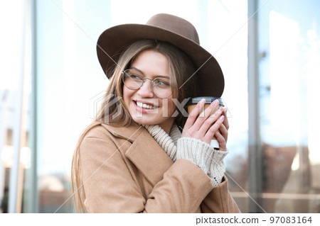 Young woman with cup of coffee on city street in morning 97083164
