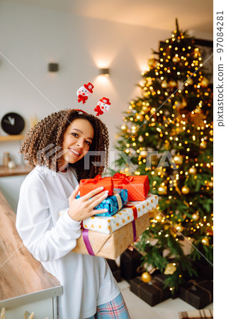 Portrait of young woman in santa claus hat with gift at the Christmas tree. Christmas. New year's. 97084281