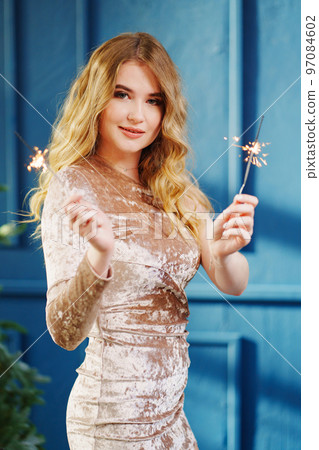 a beautiful woman with sparklers in a blue room with a Christmas tree. a beautiful woman with sparklers in a blue room with a Christmas tree. 97084602