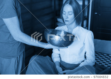 Man holding tibetan singing bowls in sound therapy in spa center 97084832