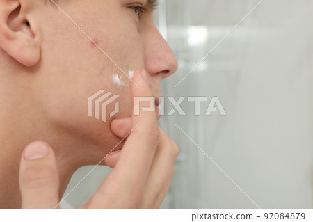 Teen guy with acne problem applying cream indoors, closeup 97084879