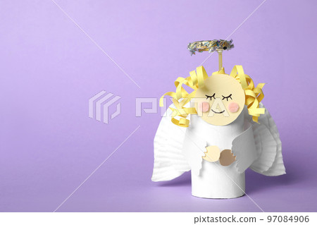 Toy angel made of toilet paper hub on lilac background. Space for text 97084906