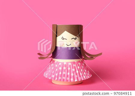 Toy doll made of toilet paper hub on pink background 97084911