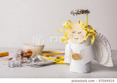 Toy angel made of toilet paper hub on white wooden table. Space for text Toy angel made of toilet paper hub on white wooden table. Space for text 97084919