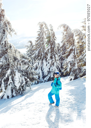 Girl in winter clothes drinking tea on the background of snow-capped mountains on the sunny day. Girl in winter clothes drinking tea on the background of snow-capped mountains on the sunny day. 97085027