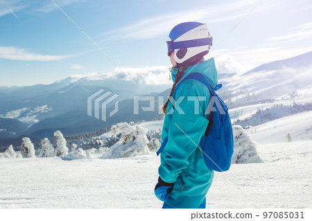 Girl in winter clothes drinking tea on the background of snow-capped mountains on the sunny day. Girl in winter clothes drinking tea on the background of snow-capped mountains on the sunny day. 97085031