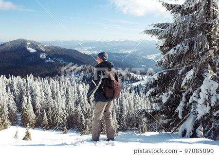 Man with backpack trekking in mountains. Cold weather, snow on hills. Winter hiking. Man with backpack trekking in mountains. Cold weather, snow on hills. Winter hiking. 97085090