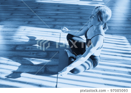Young woman meditating sitting in lotus position against sunny window 97085093