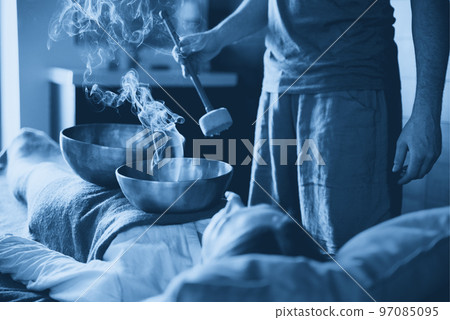 Tibetan singing bowls with smoke in sound therapy in spa center 97085095
