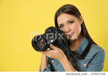 Professional photographer working on yellow background in studio Professional photographer working on yellow background in studio 97085708