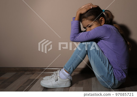Scared little girl near beige wall, space for text. Domestic violence concept Scared little girl near beige wall, space for text. Domestic violence concept 97085721