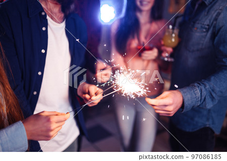 Group of friends having fun with sparklers. young people laugh. celebrating New Year together. 97086185