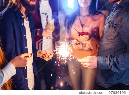 Group of friends having fun with sparklers. young people laugh. celebrating New Year together. 97086193