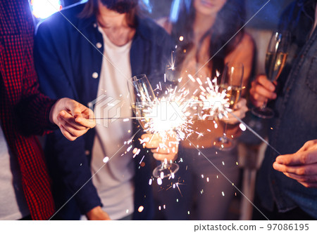 Group of friends having fun with sparklers. young people laugh. celebrating New Year together. 97086195