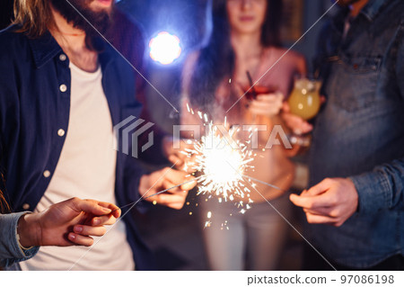 Group of friends having fun with sparklers. young people laugh. celebrating New Year together. 97086198