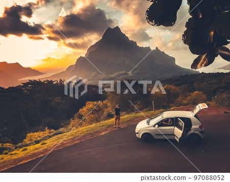 Car travel concept. People watching sunset over mountain peak on tropical Moorea island, Polynesia. Majestic sunset of the mountains landscape. Stunning wild nature during sunrise. Vintage retro tone. Car travel concept. People watching sunset over mountain peak on tropical Moorea island, Polynesia. Majestic sunset of the mountains landscape. Stunning wild nature during sunrise. Vintage retro tone. 97088052