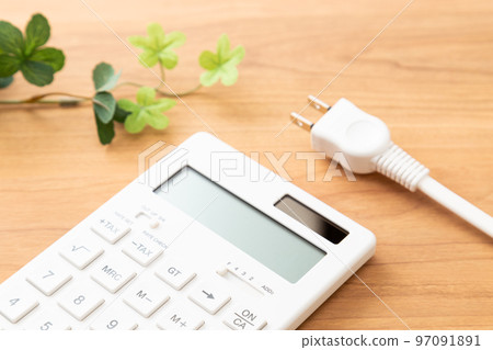 Calculator and outlet plug on the desk, wood grain background 97091891