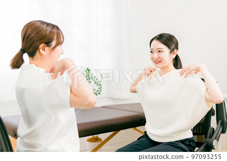 Female doctor, physiotherapist, nurse and patient receiving stretching and gymnastics rehabilitation guidance at a chiropractic clinic / osteopathic clinic with stiff shoulders 97093255