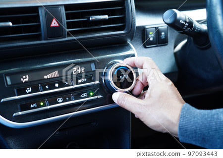 Asian woman driver tuning temperature control air condition system in car. 97093443