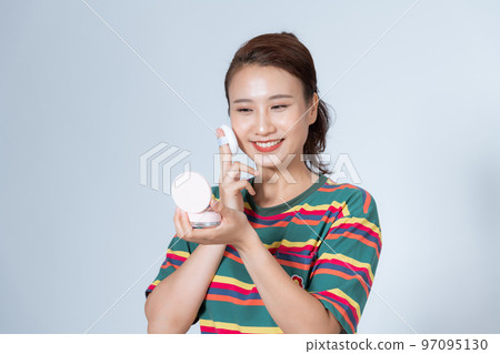 Asian concentrated woman is using blender sponge while looking in the mirror. 97095130