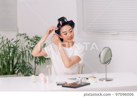 Young woman using hair curlers Young woman using hair curlers 97096006